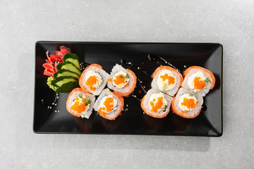 Philadelphia roll sushi with salmon, avocado, cream cheese and red caviar. Sushi menu. on dark plate. Traditional japanese seafood, healthy food concept. Top view horizontal photo on white background.