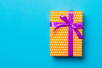 Top view Christmas present box with purple bow on blue background with copy space