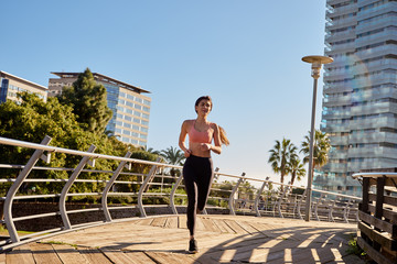 Woman runs on a wooden path with metal railings