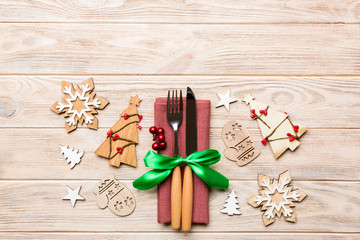 Top view of fork and knife tied up with ribbon on napkin on wooden background. Christmas decorations and New Year tree. Happy holiday concept with empty space for your design