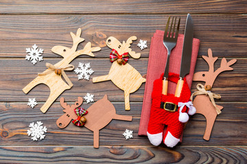 Top view of new year utensils on napkin with holiday decorations and reindeer on wooden background....