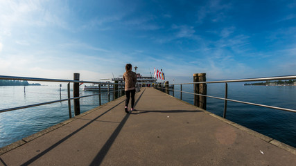 Fototapeta na wymiar A Woman walking on the pier at Kressbronn am Bodensee