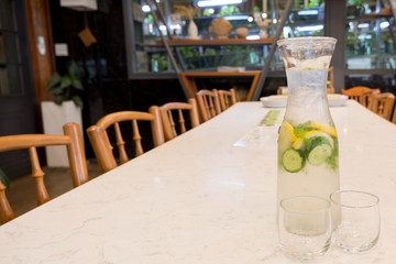 Herbal water, cucumber, lemon, mint in a pitcher with two glasses on the restaurant table
