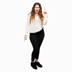 Fototapeta premium Young beautiful woman wearing glasses pointing finger up with successful idea. Exited and happy. Number one.