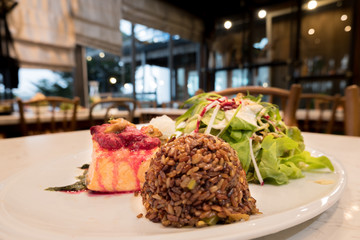 Salmon fish steak, Organic vegetable salad and rice Raspberry in a white dish with mashed potatoes