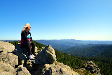 Obraz premium Hiker sitting on rock.Tourist on the top of Grosser Arber mountain in National park Bayerischer wald, Germany.
