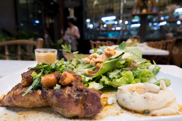 Pork steak, hot dog and organic salad In a white dish with mashed potatoes