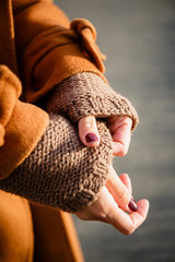 girl straightens the sleeves of a brown knitted sweater. beautiful female hands with manicure froze in the cold