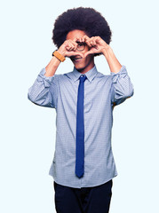 Young african american business man with afro hair wearing glasses Doing heart shape with hand and fingers smiling looking through sign