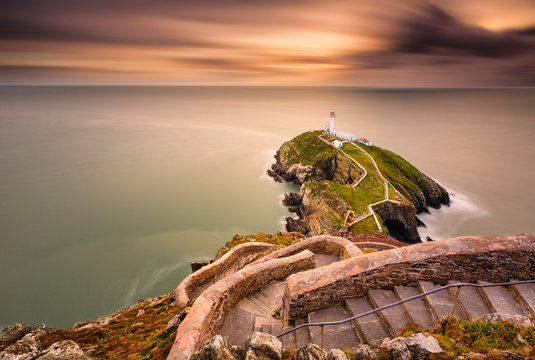 Lighthouse on coastal island with horizon and beautiful sunset at South Stack in Holyhead, North Wales. South Stack lighthouse at sunset overlooking the Irish Sea Isle of Anglesey