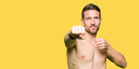 Fototapeta premium Handsome shirtless man showing nude chest Punching fist to fight, aggressive and angry attack, threat and violence