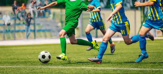 Obraz na płótnie Canvas Junior level football competition. School soccer tournamrnt. Group of boy running after ball on rummer day