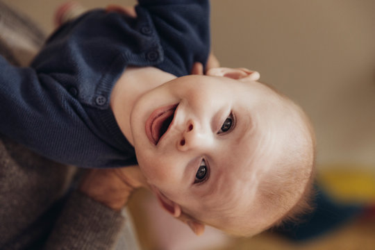 Baby wird von einem Mann gehalten und streckt den Nacken durch