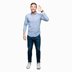 Handsome business man with blue eyes smiling positive doing ok sign with hand and fingers....