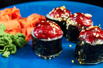 maki in nori with baked sauce hat on blue plate