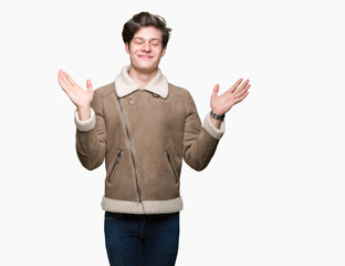 Young handsome man wearing winter coat over isolated background Smiling showing both hands open palms, presenting and advertising comparison and balance