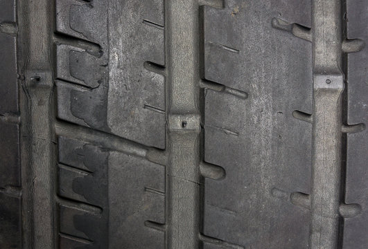 Close up of worn tire with tread wear indicator, minimum legal tread depth 