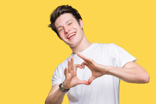 Young handsome man wearing casual white t-shirt over isolated background smiling in love showing heart symbol and shape with hands. Romantic concept.