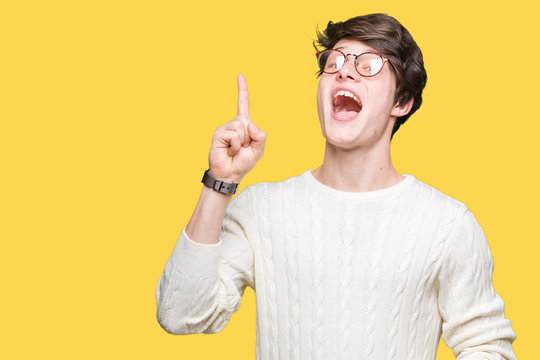 Young handsome man wearing glasses over isolated background pointing finger up with successful idea. Exited and happy. Number one.
