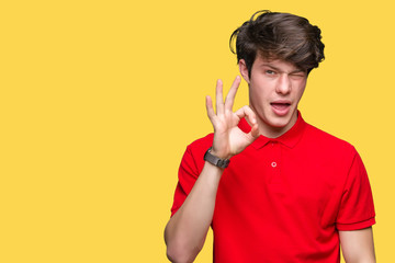 Young handsome man wearing red t-shirt over isolated background winking looking at the camera with...