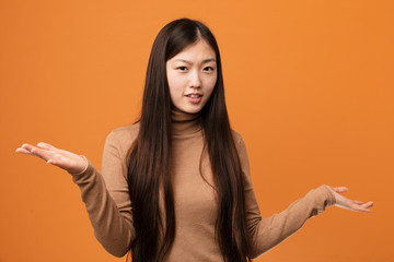 Young pretty chinese woman doubting between two options.