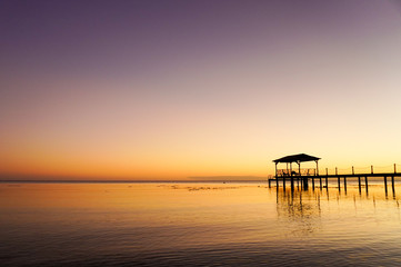 A dock over water at sunset on the island of Fakarava in French Polynesia in the South Pacific