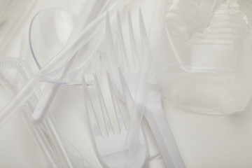 close up view of crumpled plastic cup, forks and spoons on white background