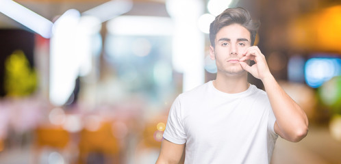 Young handsome man wearing white t-shirt over isolated background mouth and lips shut as zip with...