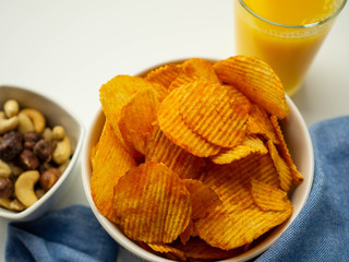 Chipsy paprykowe z orzechami i sokiem. Pyszna przekąska do filmu. Widok z górym, białe tło.