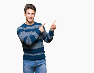 Young handsome man over isolated background smiling and looking at the camera pointing with two hands and fingers to the side.