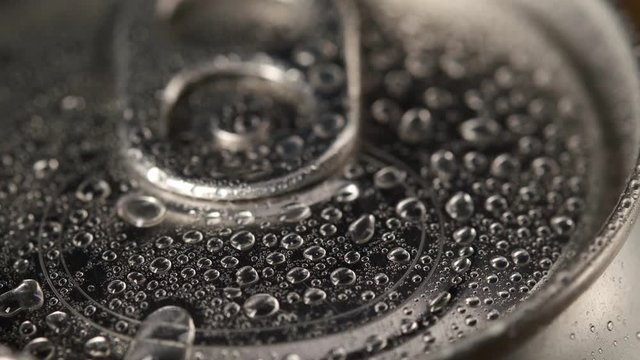 Close-up camera shoots shiny aluminum can, macro shot, surface of can is wet, in droplets of water, light will be reflected from metal, beer can, can from soda, modern packaging