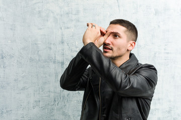 Young rocker man looking far away keeping him hand on forehead.