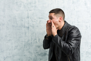 Young rocker man shouts loud, keeps eyes opened and hands tense.