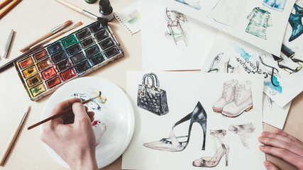 Fashion sketching. Women clothing design. Male artist painting with watercolors.