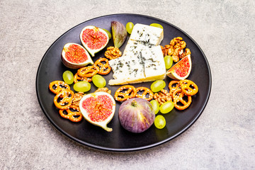 Cheese plate with blue cheese, walnuts, figs, grapes, pretzels