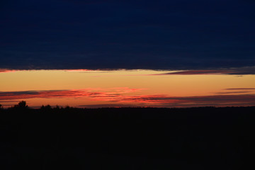 Dawn, dark sky, streak of the sun, contrasting earth, three colors