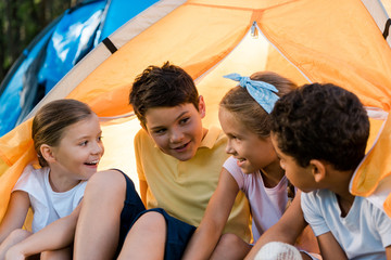 happy multicultural kids sitting in yellow camp