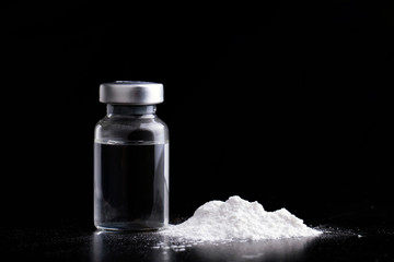 Vial of vaccine with drug powder in black background.GHB