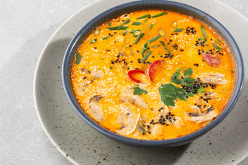 Tom Yam kung Spicy Thai soup with shrimp, seafood, coconut milk and chili pepper in bowl. In gray stone background. Horizontal photo.