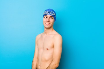 Young swimmer man looks aside smiling, cheerful and pleasant.