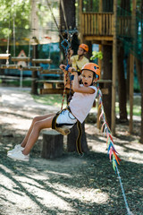 selective focus of happy and cute kid in helmet riding in adventure park