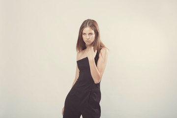 Fototapeta premium Fashionable girl in light tones in studio. Woman with unflappable face. Lifestyle concept in fashion world. Female in suit