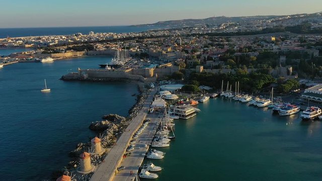 Aerial birds eye view drone video of Rhodes city island, Dodecanese, Greece. Panorama with Mandraki port, lagoon and clear blue water. Famous tourist destination in South Europe.