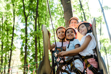 cheerful multicultural kids looking up in adventure park outside