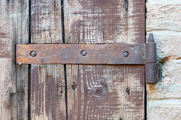 Window detail of rural house, with cracked paint and rusty hinges, on brick wall and ancient stones.