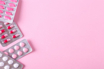 Flat lay composition with bunch of different colorful pills in blister packs. Pile of unpacked medication on paper textured background. Close up, copy space.