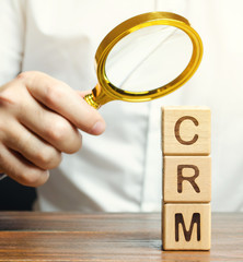 Wooden blocks with the word CRM (Customer Relationship Management) and businessman. Automation...