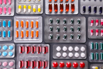 Flat lay composition with bunch of different colorful pills in blister packs. Pile of unpacked medication on paper textured background. Close up, copy space. - obrazy, fototapety, plakaty