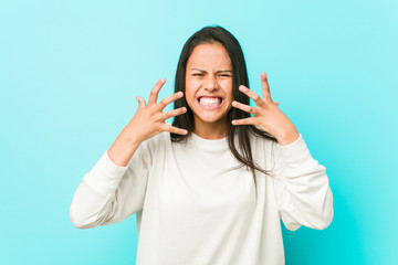 Young pretty hispanic woman upset screaming with tense hands.