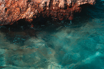 Sharp stones and rocks in the turquoise, blue sea. Brutal, orange-turquoise beautiful seascape. Aegean coast in Turkey. Bodrum.